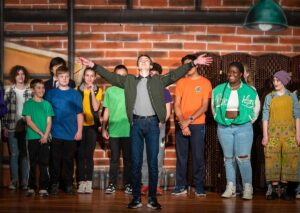 An actor with arms outstretched onstage