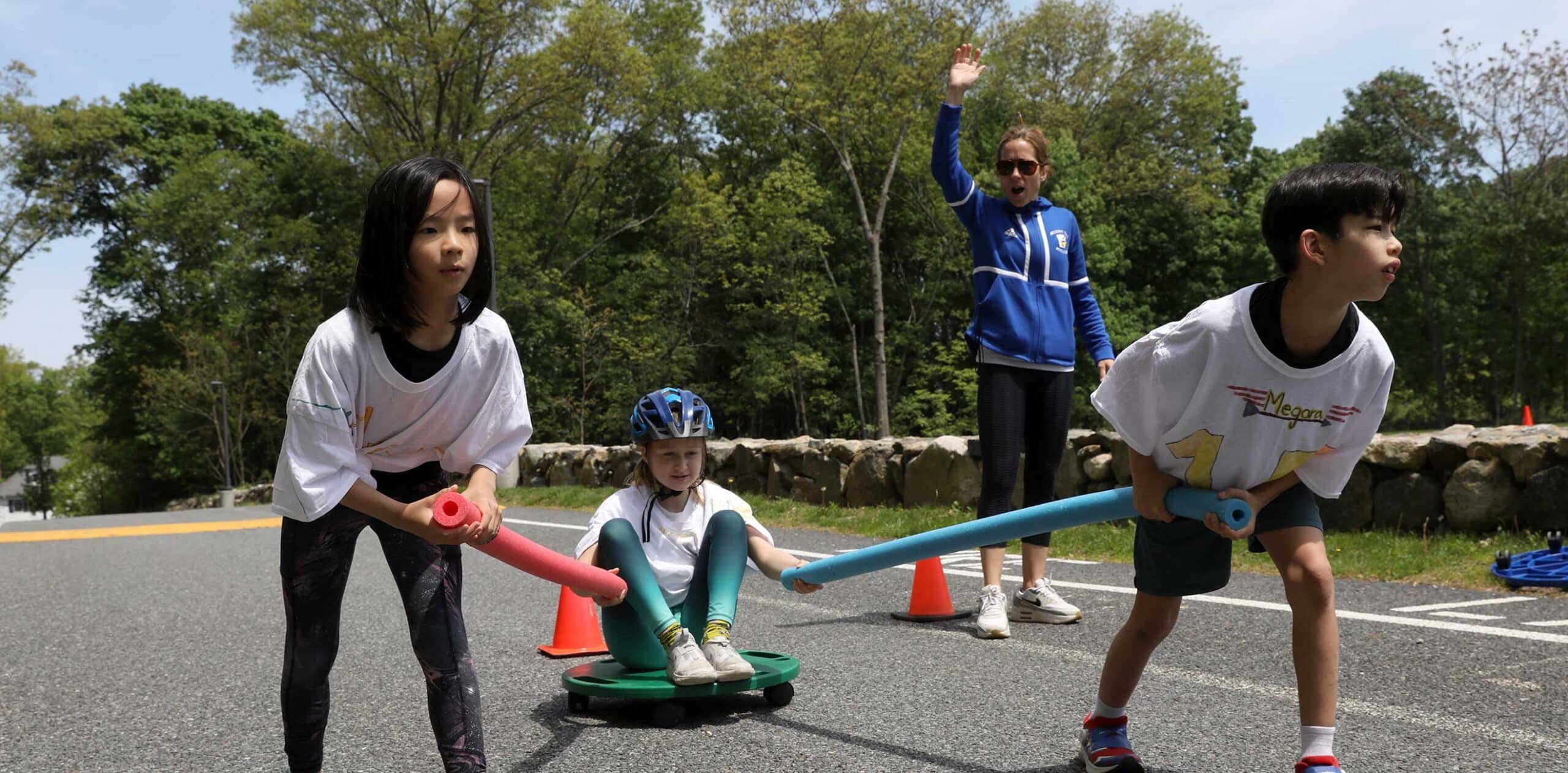 Fourth graders and a coach complete a Greek Olympics challenge