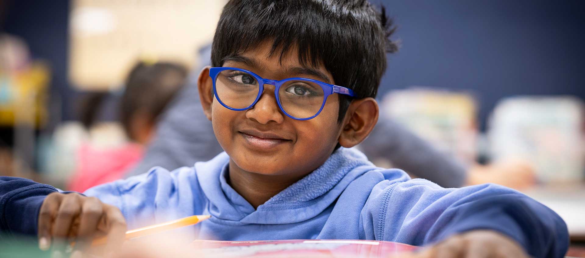 A boy wearing glasses looks at the camera